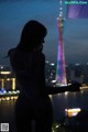 A woman standing in front of a city at night.