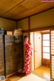 A woman in a red kimono standing in a room.