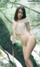 A woman in lingerie posing on a tree branch.
