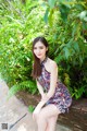 A woman sitting on a stone wall in a dress.