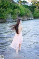 A woman in a pink dress standing in the water.