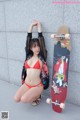 A woman in a red bikini posing next to a skateboard.