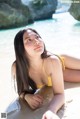 A woman in a yellow bikini laying on the beach.