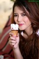 A woman holding an ice cream cone in her hand.