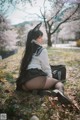 A woman in a school uniform sitting on the ground.