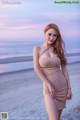 A woman in a beige dress standing on a beach.