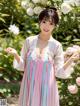 a woman in a pink and blue dress standing in front of flowers