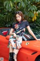 A woman sitting on top of a red sports car.