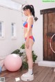 A woman in a red, white and blue bikini standing next to a pink ball.