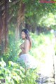 A woman in a white dress standing in the woods.