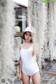 A woman in a white bathing suit and a white hat.