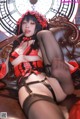 A woman in a red and black lingerie sitting on a brown couch.