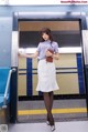 A woman standing in front of an elevator holding a purse.