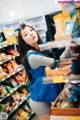 A woman in a blue vest is standing in a grocery store.