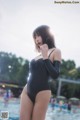 A woman in a black bathing suit standing in a pool.