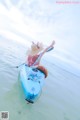 A woman in a straw hat is floating in a blue kayak.