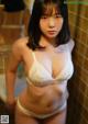 A woman in a white bra and panties standing in a bathroom.