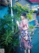 A woman standing in front of a green plant.