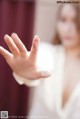 A woman in a white robe holding out her hand.