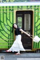 A woman standing in front of a green and white train.