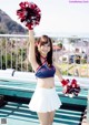 A woman in a cheerleading uniform holding a pom pom.