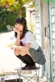 A woman in a school uniform sitting on a chair.