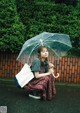 A woman sitting on the ground holding an umbrella.