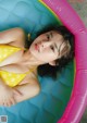 A woman in a yellow bikini laying in an inflatable pool.