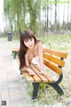 A woman sitting on a wooden bench in a park.