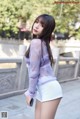 A woman in a purple sweater and white shorts posing for a picture.