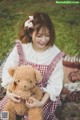 A girl in a red and white dress holding a teddy bear.