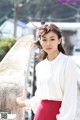 A woman in a white blouse and red skirt posing for a picture.