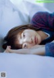 A young woman laying on a bed with her eyes closed.