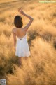 A woman in a white dress standing in a field of tall grass.