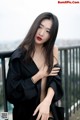 A woman in a black dress posing on a balcony.