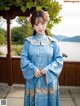 A woman in a blue chinese dress standing on a porch.